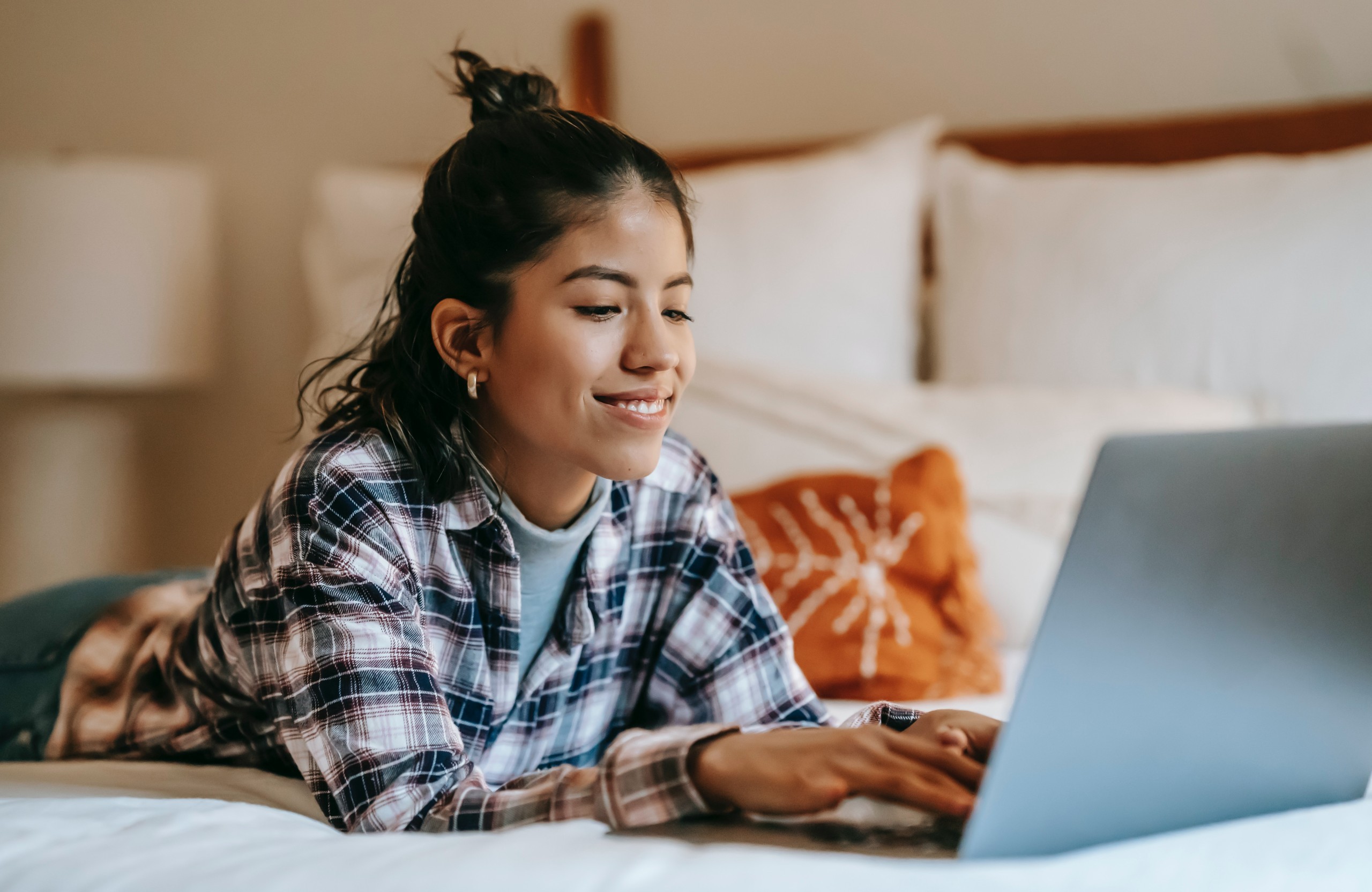 hispanic woman in a plaid shirt on her laptop